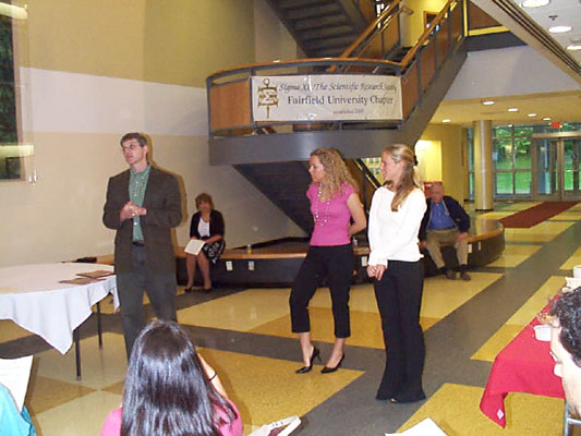 Professor Glenn Sauer presents certificates and cords to students Alison Sikora and Maryellen Pribish